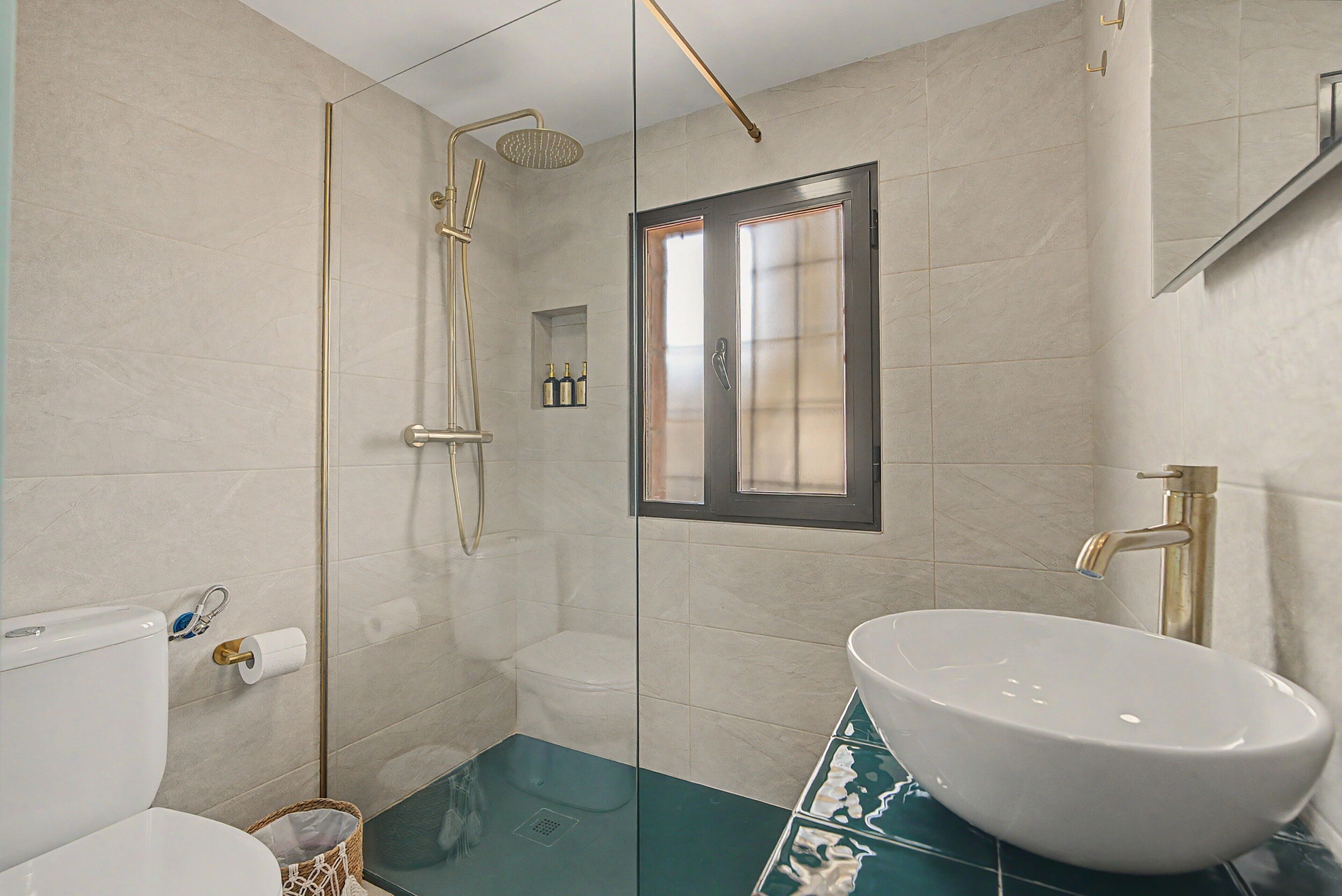 Une salle de bain moderne avec une douche à parois de verre, un lavabo blanc et une petite fenêtre.