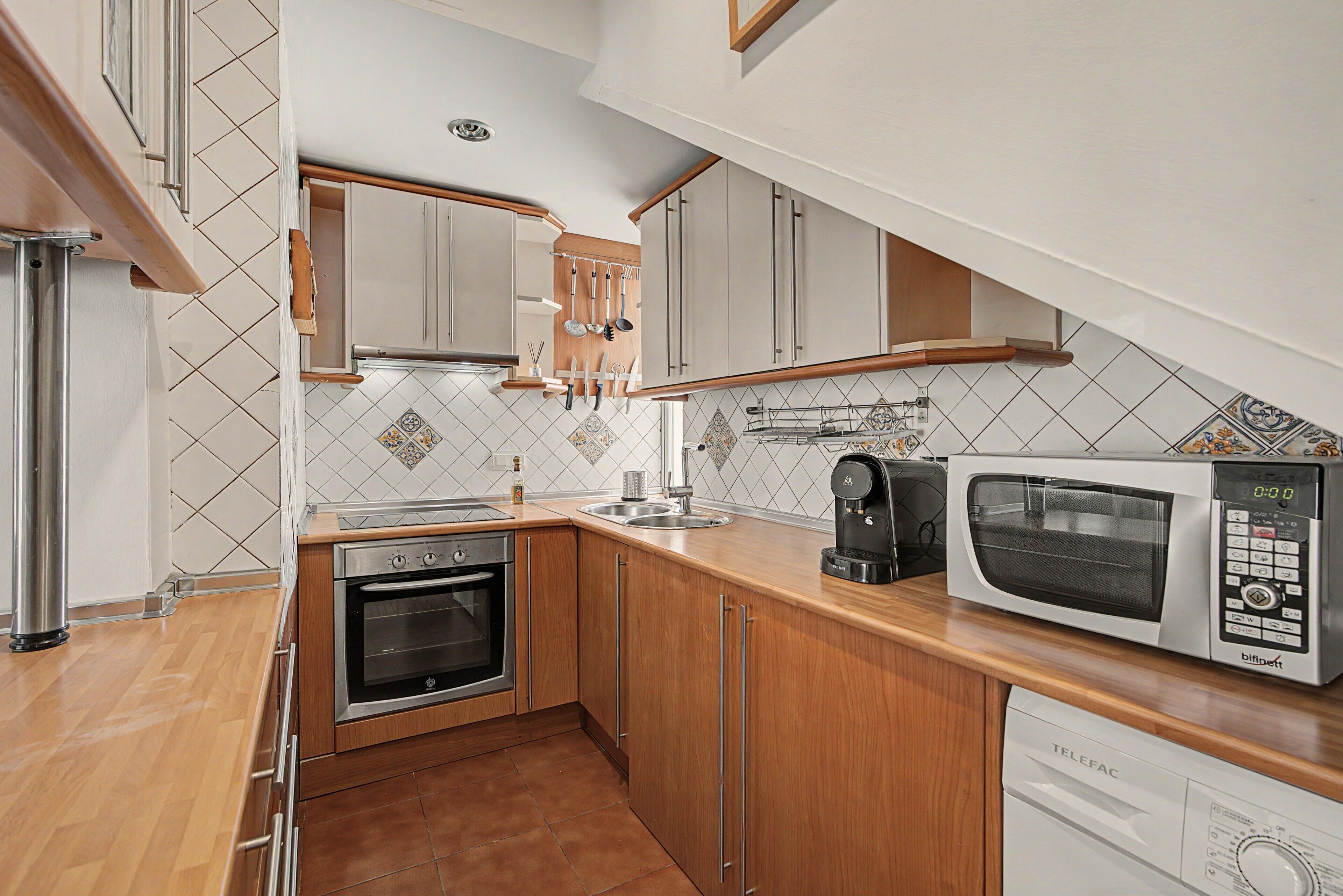 A compact kitchen with a built-in oven, a microwave, and a coffee maker.