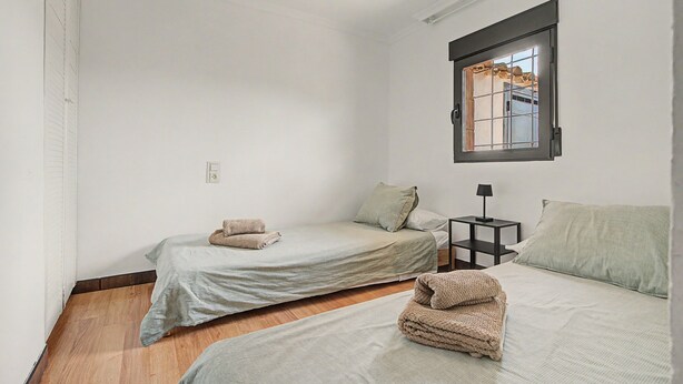 A room with two beds, a small table, and a window.