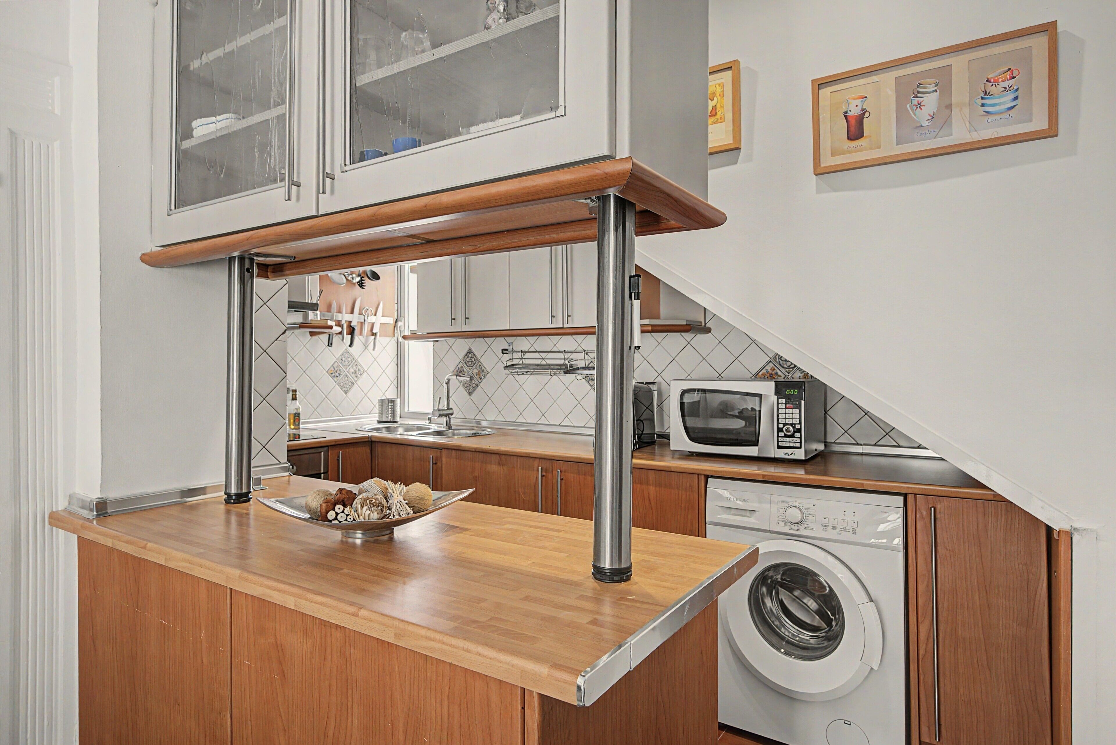 A compact kitchen with a wooden countertop, a built-in washing machine, and a microwave.