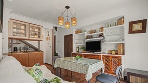 A compact living space with a dining area, kitchenette, and a television.