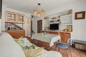 A compact living space with a dining area, kitchenette, and a television.