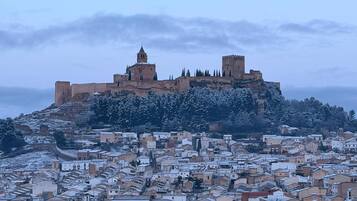 Un castillo histórico en una colina con vistas a un pueblo con tejados cubiertos de nieve.