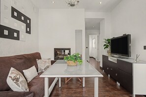 A modern living room with a sofa, a coffee table, a flat-screen TV, and a fireplace.