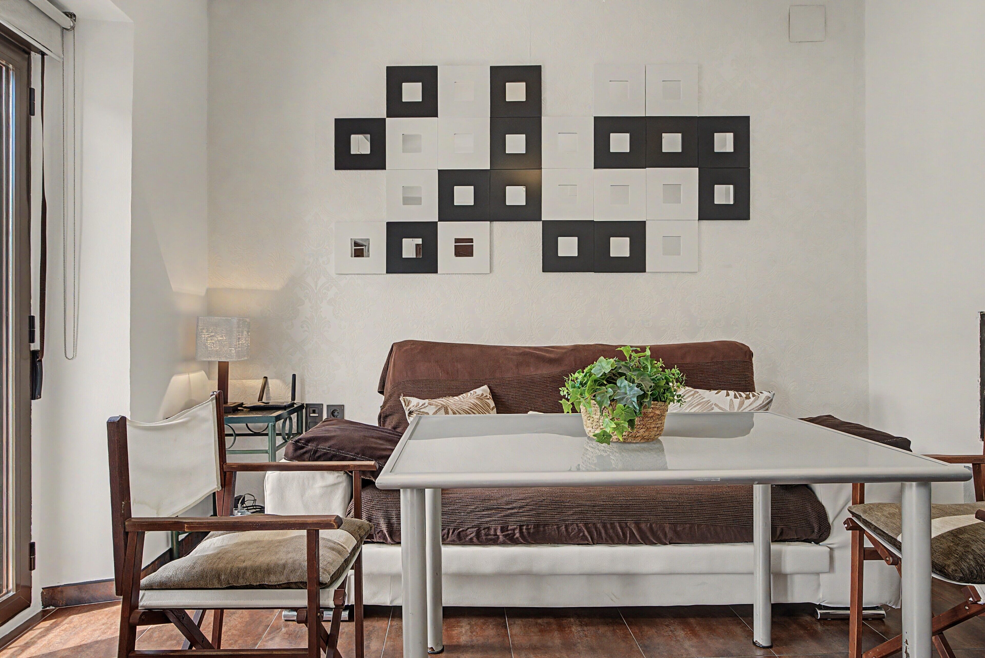 Un salon moderne avec un canapé blanc, une table basse et un luminaire fixé au mur.