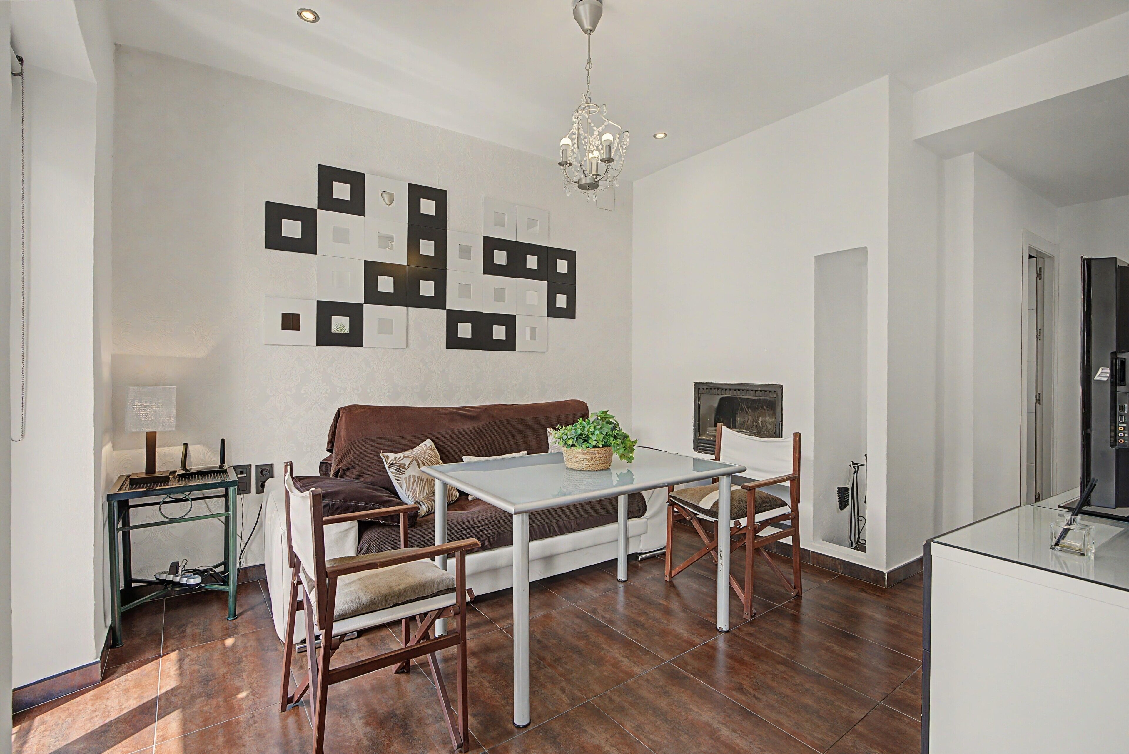 Un salon moderne avec un coin repas, comprenant un canapé, une table basse et un lustre.
