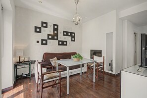 En moderne stue med spiseplads, der indeholder en sofa, et sofabord og en lysekrone.
