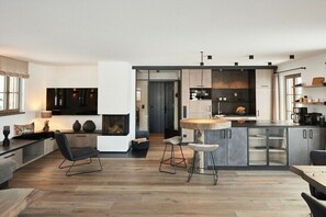 Eine moderne Küche mit Kochinsel, Barhocker und Kamin.
