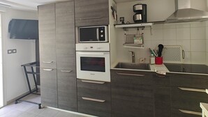 A modern kitchen with a built-in oven, microwave, and a stainless steel range hood. - Near Bordeaux: air conditioning, parking, and a picturesque setting (Latresne)