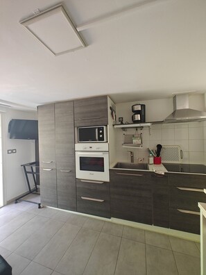 A modern kitchen with a built-in oven, microwave, and a stainless steel range hood. - Near Bordeaux: air conditioning, parking, and a picturesque setting (Latresne)