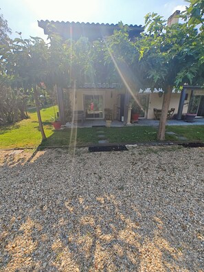 A building with a covered entrance, a gravel driveway, and a grassy area. - Near Bordeaux: air conditioning, parking, and a picturesque setting (Latresne)