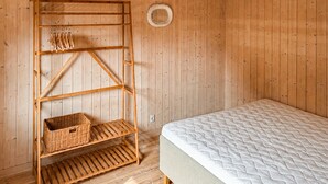 Une pièce en bois avec un lit, une étagère en bois avec des paniers et un élément de décoration circulaire fixé au mur.