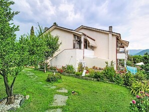 Une maison à deux étages avec un jardin, un escalier apparent et un balcon.