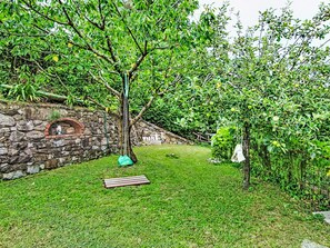 A stone wall, a swing, and a grassy yard with trees. - Cà Olivella by Interhome (Casarza Ligure)