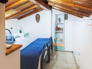 Une chambre à coucher comprenant un lit, une table de chevet, une commode, un miroir et un plafond avec des poutres en bois.