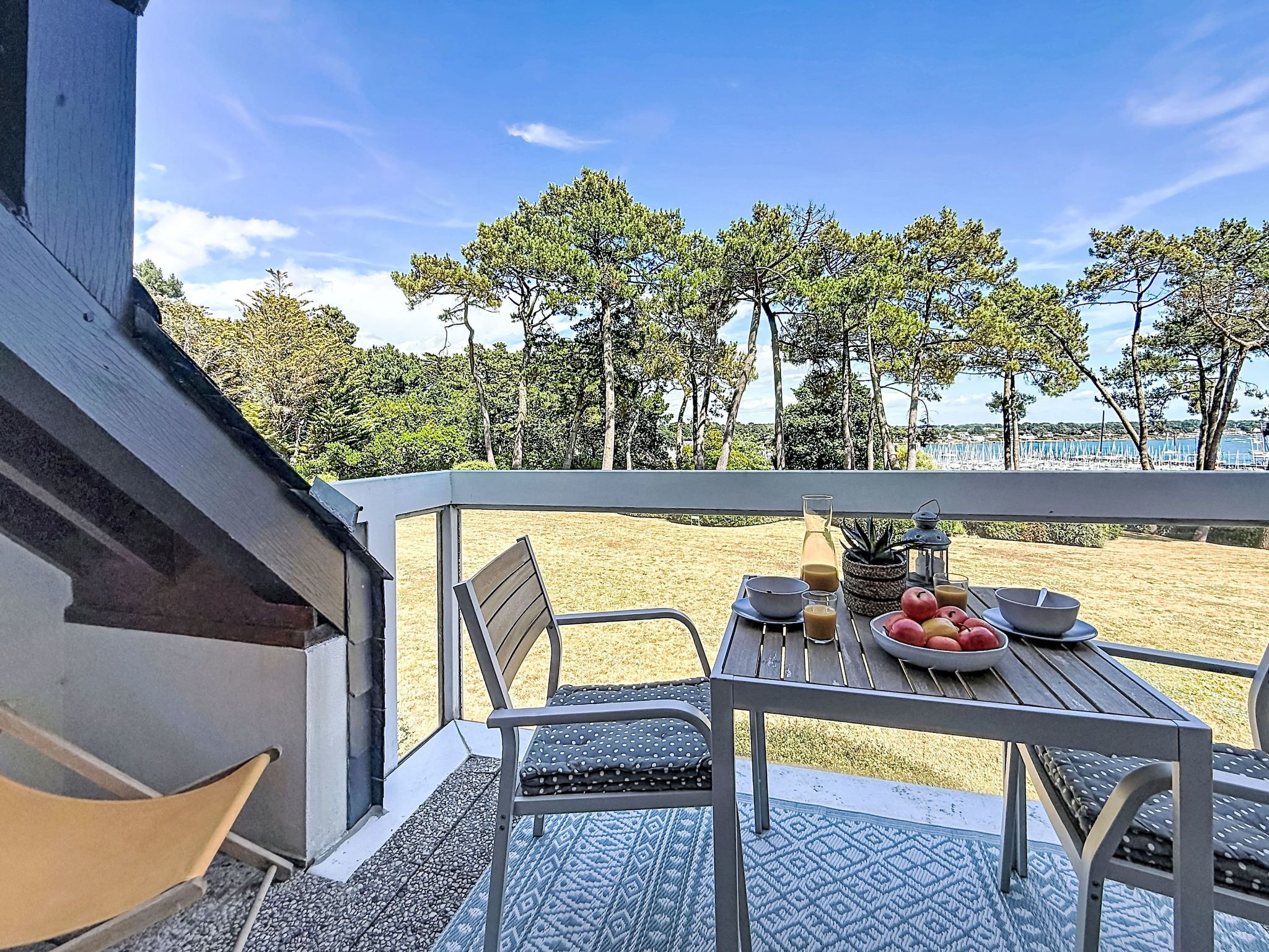Une terrasse avec une table dressée pour le repas, donnant sur une plage et des arbres.