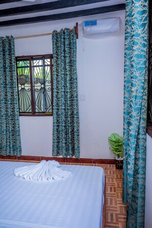 A room with a bed, a window with metal bars, patterned curtains, a potted plant, and a wall-mounted air conditioner. - Marumbi Beach House (Marumbi)