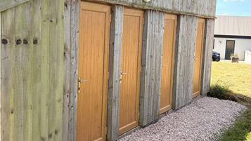 A wooden building with four doors, a gravel driveway, and a grassy area.