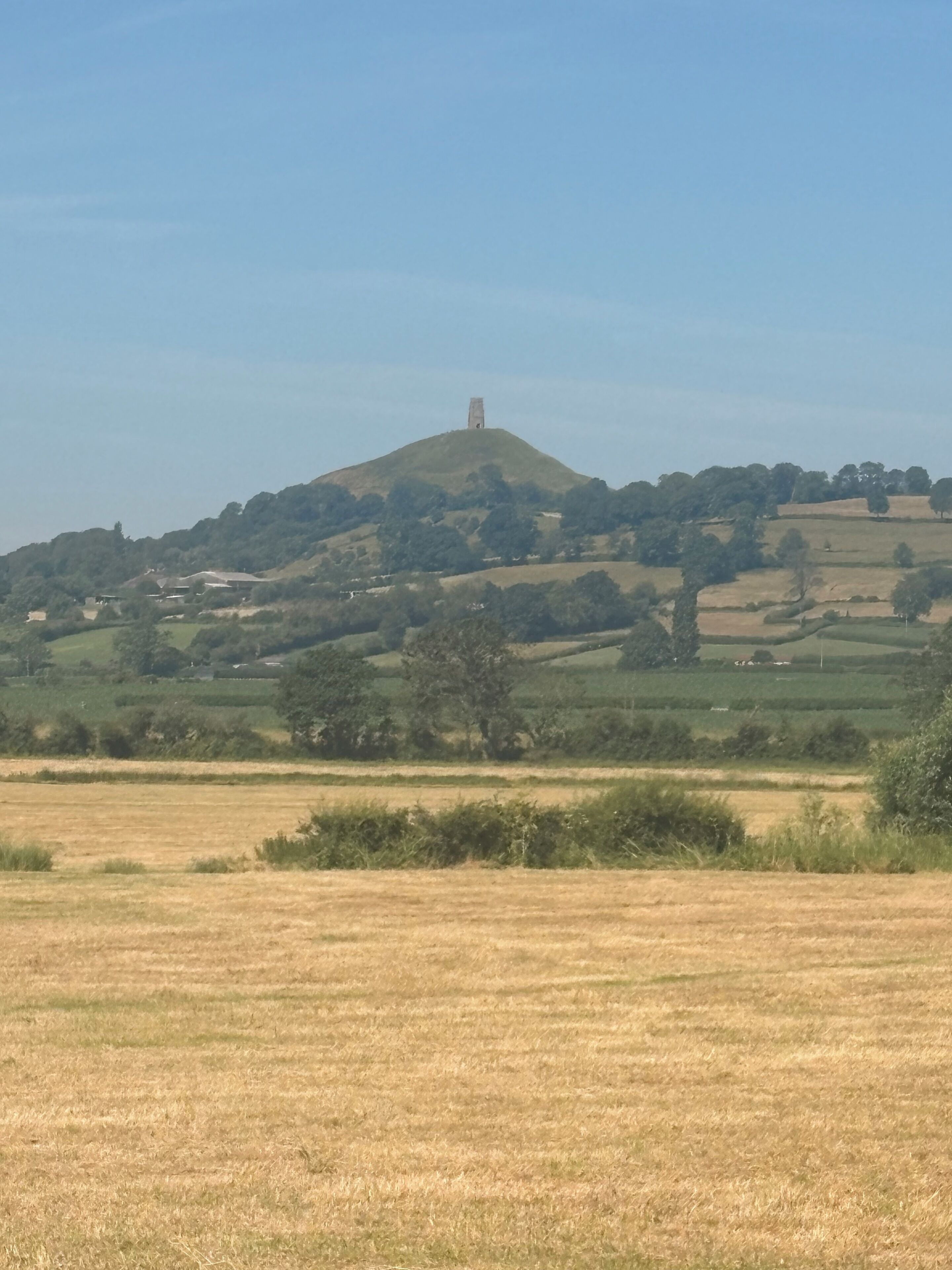 A rural landscape with a hill and a tower-like structure on top.
