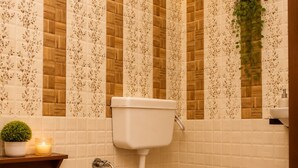 A bathroom with a toilet, wooden floor, and patterned walls.