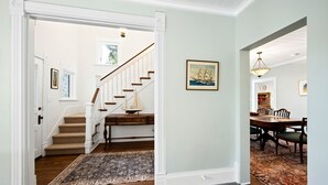 A hallway with a carpeted staircase, a dining area with a table and chairs, and a framed picture on the wall. - Spacious 4BR/3BA home, blocks to downtown, parks, beach & farmers market. Fenced yard, pets welcome (Sturgeon Bay)