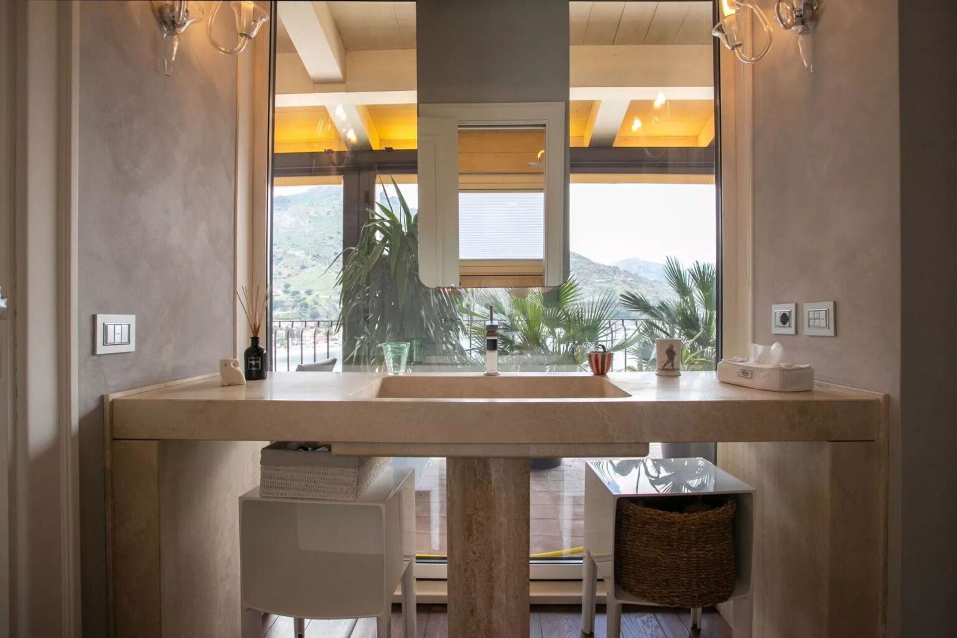 Ein Badezimmer mit großem Fenster, Waschbecken, Spiegel und Pendelleuchte.