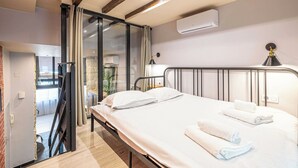 Ein Hotelzimmer mit Bett, Schreibtisch, Stuhl, Fenster und Klimaanlage.