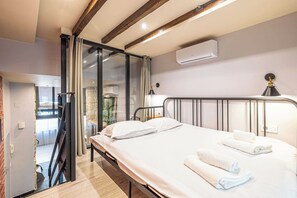 Ein Hotelzimmer mit Bett, Schreibtisch, Stuhl, Fenster und Klimaanlage.
