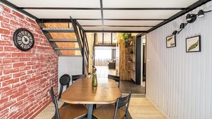 Ein Essbereich mit Backsteinwand, Holztisch und Stühlen.