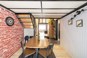 Ein Essbereich mit Backsteinwand, Holztisch und Stühlen.