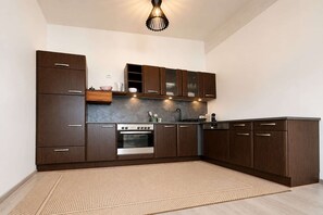 A modern kitchen with dark wood cabinets, a stainless steel oven, and a light-colored floor.