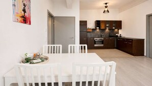 A modern kitchen with dark cabinets, a built-in oven, and a dining area with a white table and chairs. - Holiday idyll on Lake Wörthersee (Maria Saal)