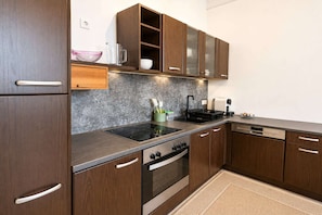 Una cocina moderna con armarios de madera, horno empotrado, estufa y lavavajillas.