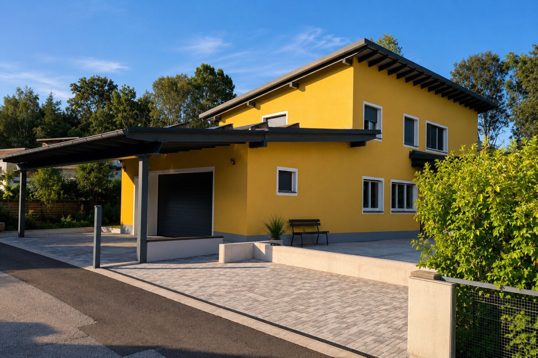 A yellow two-story house with a covered patio and a bench.