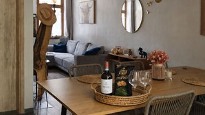A dining area with a wooden table, wicker chairs, a bottle of wine, and a glass set. - The cozy little house in Theux, near Spa, the F1 circuit, and other attractions (Theux)