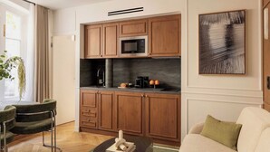 Una cocina moderna con armarios de madera, microondas integrado y cafetera. Hay un comedor con una mesa redonda y dos sillas.