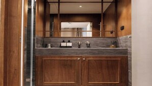 Un baño moderno con tocador de madera, un espejo y zona de ducha.