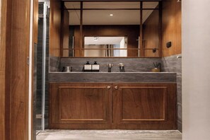 Ein modernes Badezimmer mit einem Holzkosmetikschrank, einem Spiegel und einer Duschkabine.