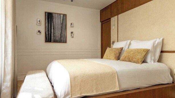 Un dormitorio ordenado con cama, mesitas de noche y cabecero.