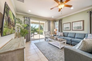 A spacious living room with a sofa, coffee table, and a ceiling fan. - Arcade Games Room + Private Pool | Mins to Disney | Cosmic Clubhouse (Kissimmee)