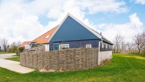 Una casa con tetto blu, muro in pietra e giardino erboso.
