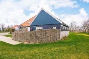 Ein Haus mit blauem Dach, einer Steinsäule und einem Rasen.