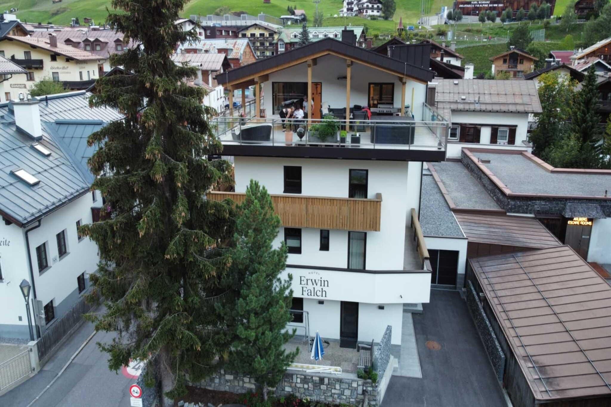 A modern hotel with a sign reading 'Erwin Falch' and a balcony with people.