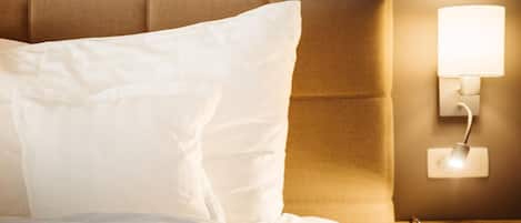 Una cama bien hecha con ropa blanca y cabecera.