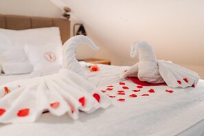 A bed with a white bedspread, a pillow with a red heart, and two white swan-shaped towels. - Relax Suite with Jacuzzi (Burg Reuland)