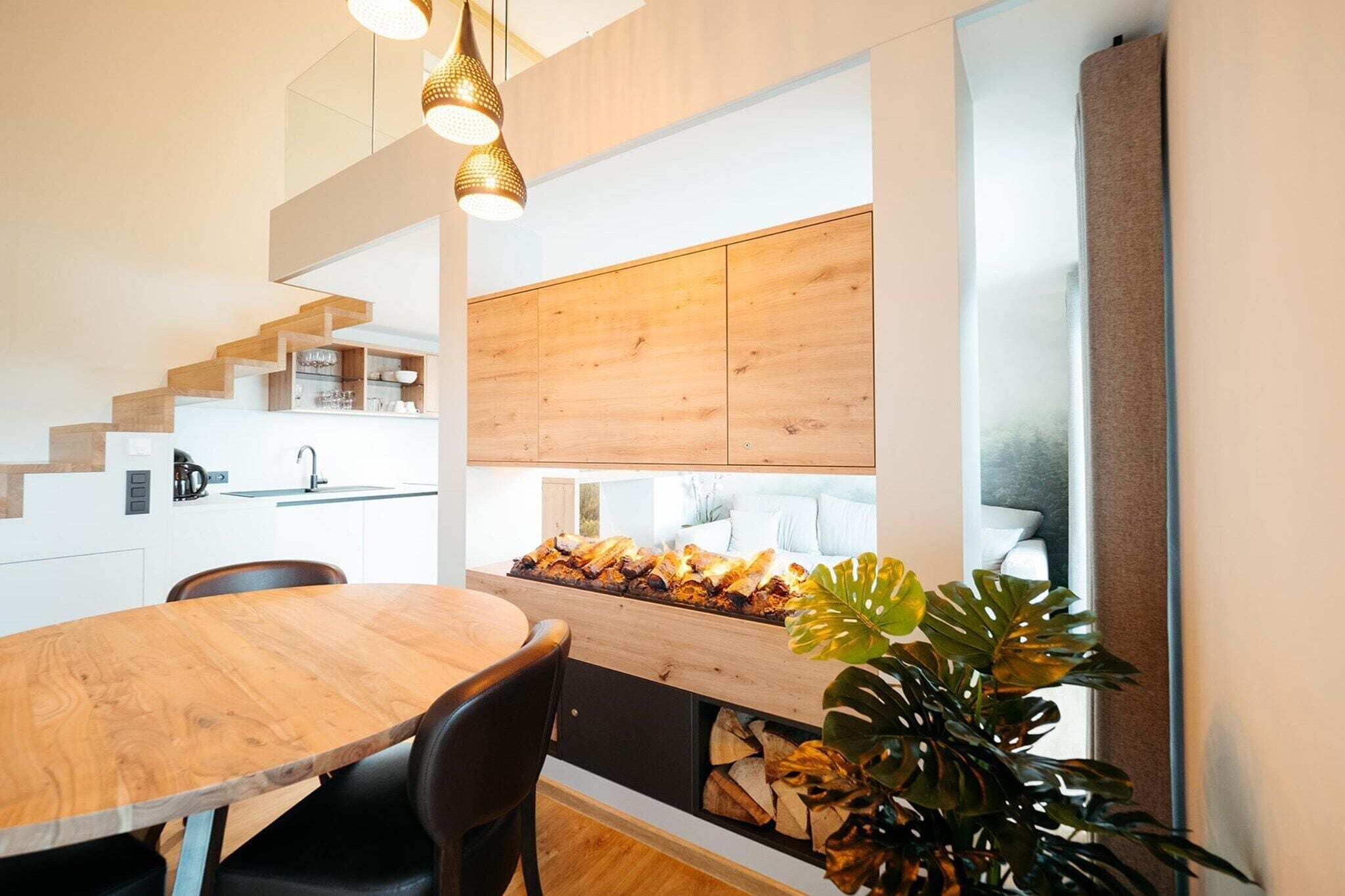 A modern kitchen with wooden cabinetry, a built-in stove, and a dining area with a wooden table and chairs.