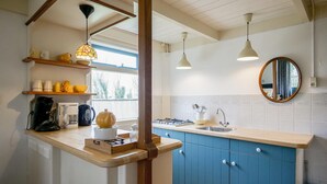 A kitchen with blue cabinets, a wooden countertop, a stove, a sink, and a window. - Holiday home in Callantsoog near beach (Callantsoog)