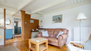 A cozy living room with a wooden coffee table, a leather sofa, and a lamp. - Holiday home in Callantsoog near beach (Callantsoog)