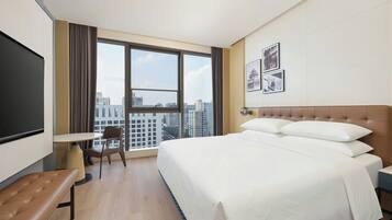 Ein Hotelzimmer mit einem großen Bett, einem Schreibtisch, einem Stuhl und einem Fernseher.