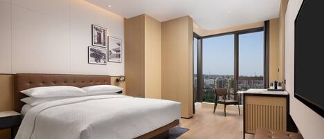 A modern hotel room with a large bed, a desk, and a view of the city.
